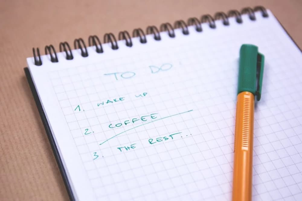 A hand-written to-do list with wake up, coffee, and the rest written in a numbered list