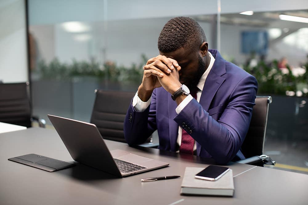 A frustrated businessman sits at his desk in front of a laptop